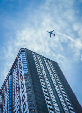 Passenger aircraft flying above a modern city building